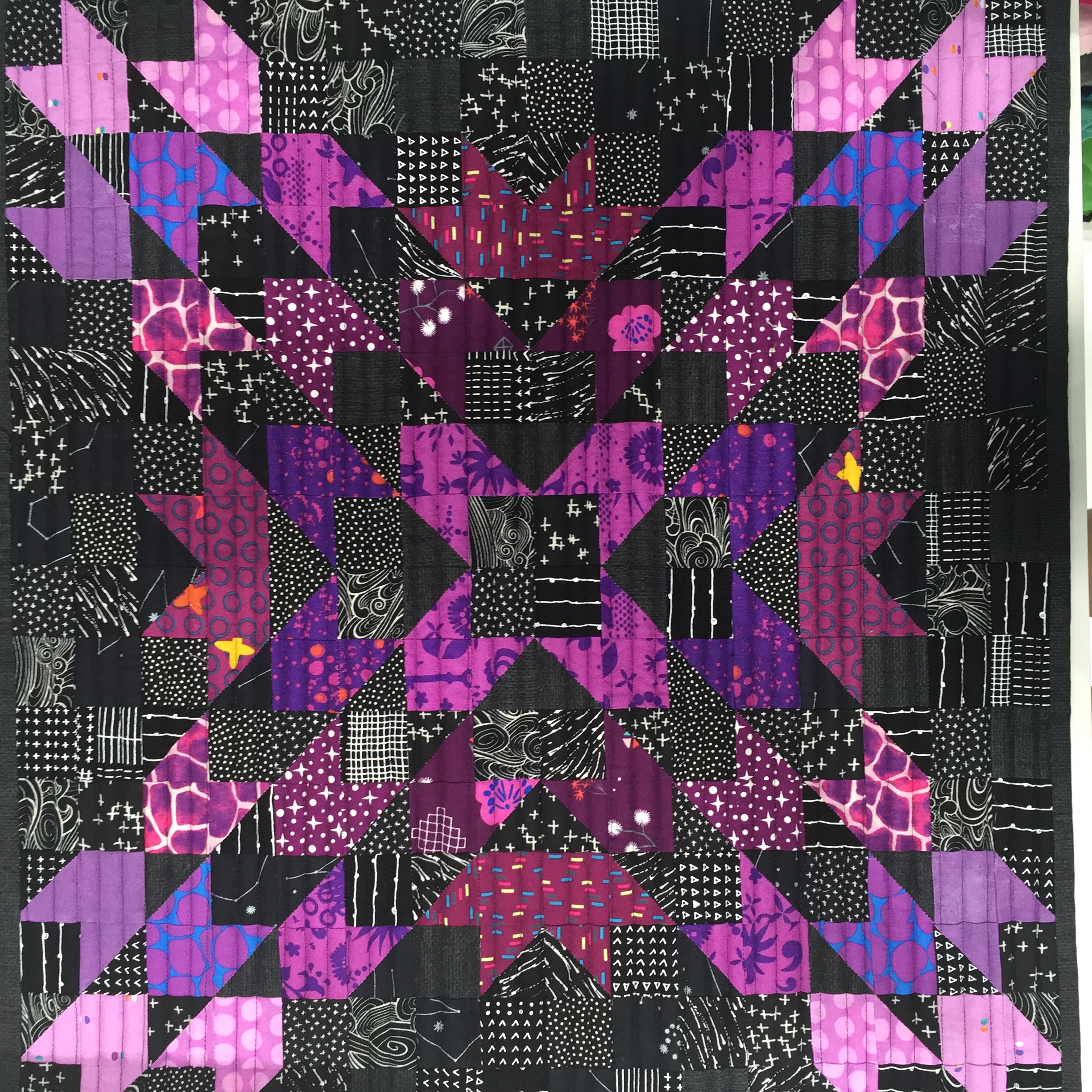 A quilt with purple and black designs on it.