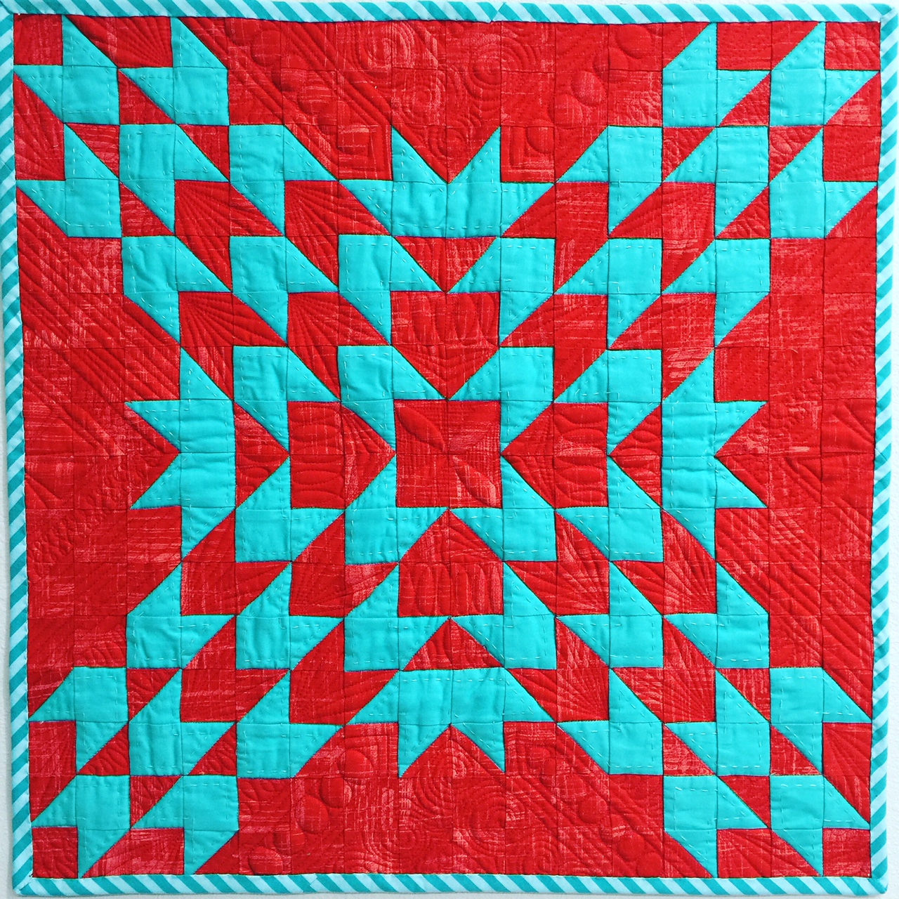 A red and blue quilt with a pattern of arrows.