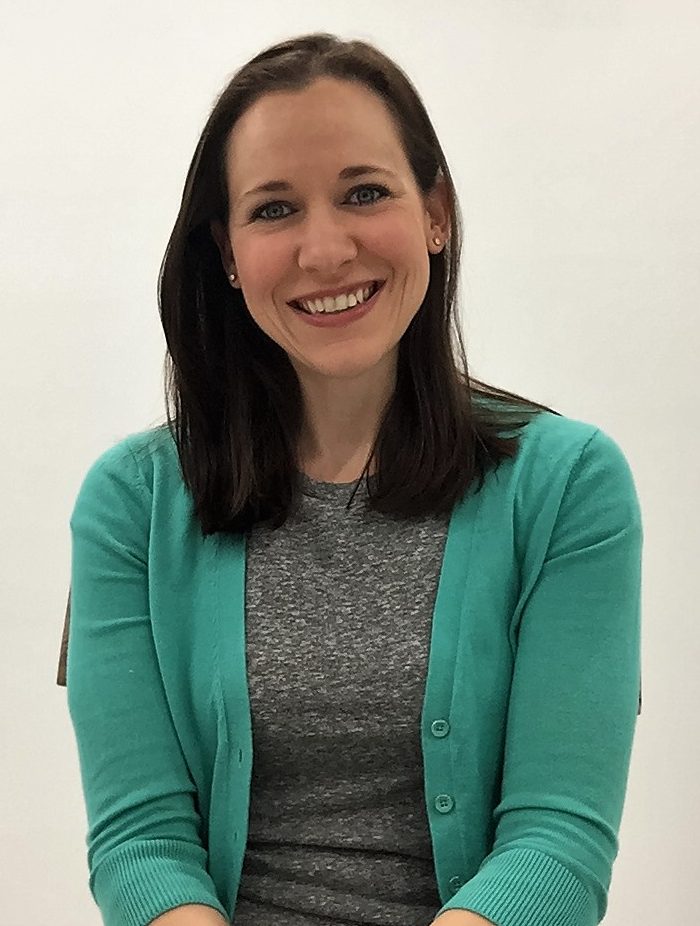 A woman in a green cardigan smiling for the camera.