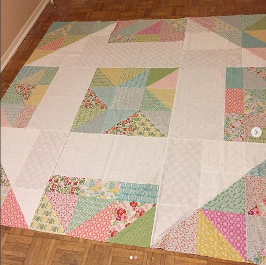 A quilt that is on the ground in a room.