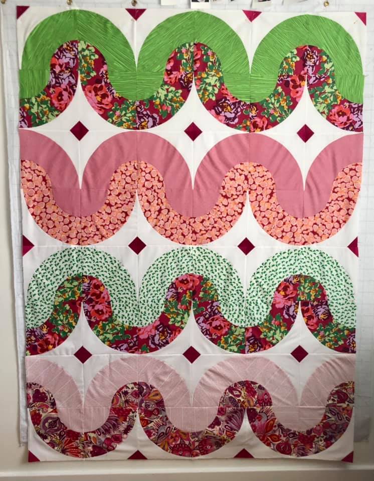 A quilt with pink and green designs on it.