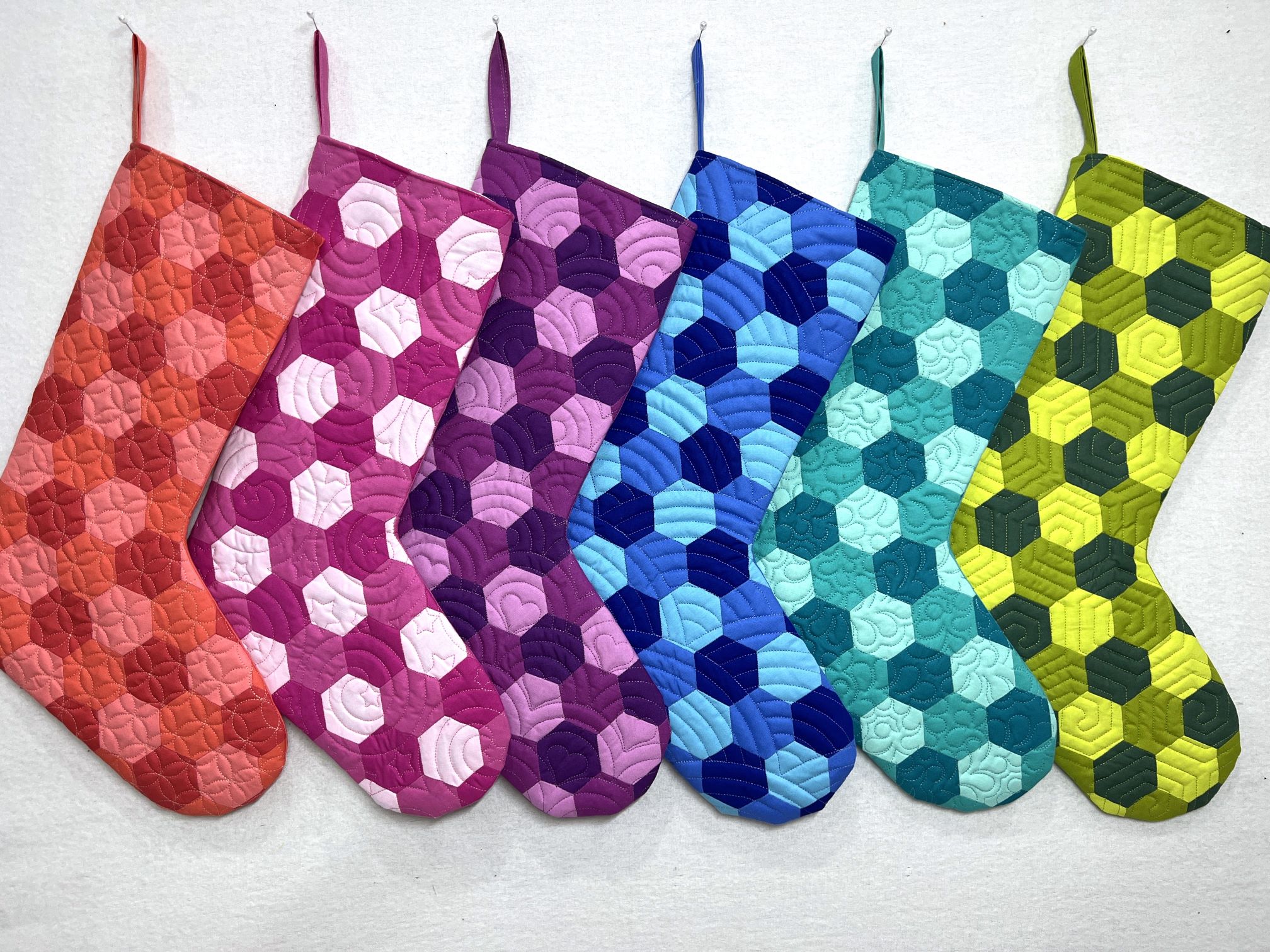 A row of colorful oven mitts in different colors.